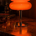 Close-up of the Aprica Table Lamp chrome stem and flat round base on burl wood