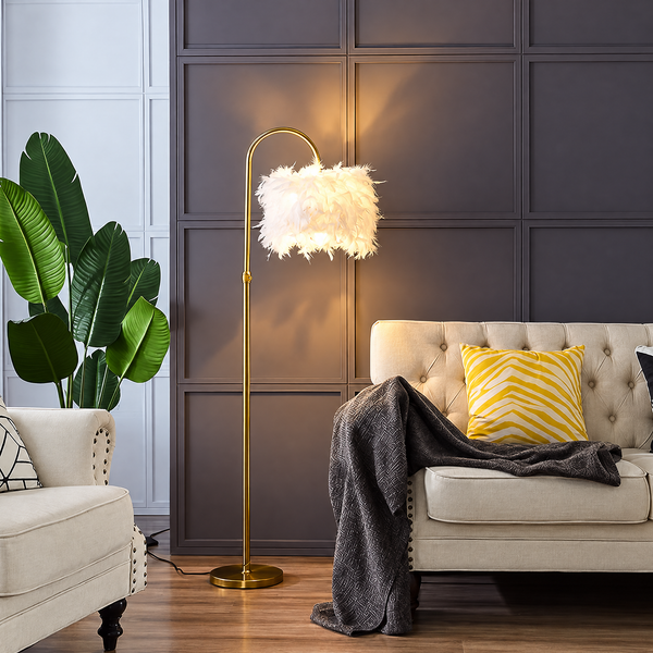 Feather lamp lit beside a cream tufted sofa, gold arched base and white feather shade