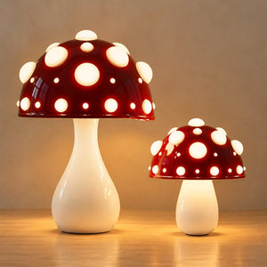 Large and small red mushroom lamps with white spots together on an oak top against a plain warm wall