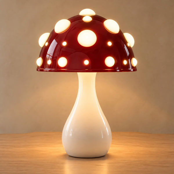 Large red mushroom lamp with white spots on an oak top against a plain warm wall