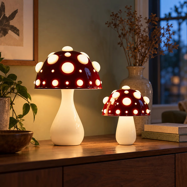 Two red mushroom lamps with white spots glowing on a walnut sideboard at dusk