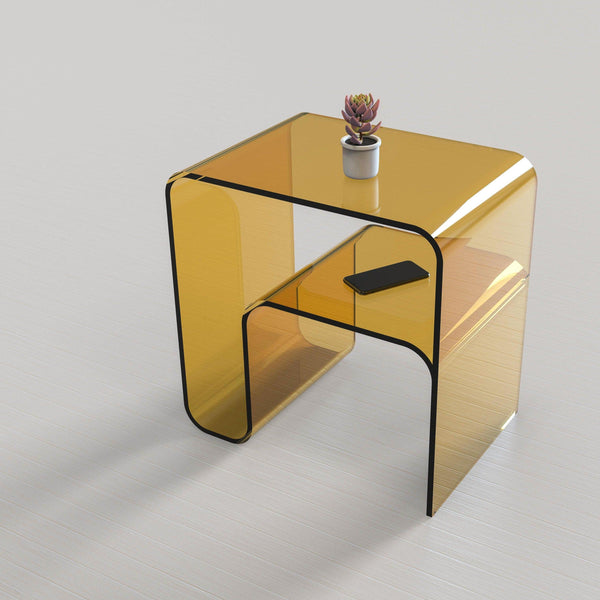 Amber acrylic side table with shelf holding a phone and small plant