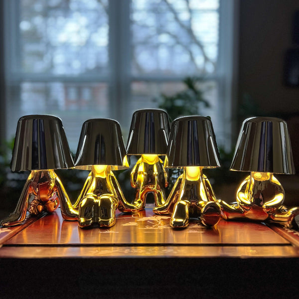 Five gold figure lamps lit in a row on a wooden table